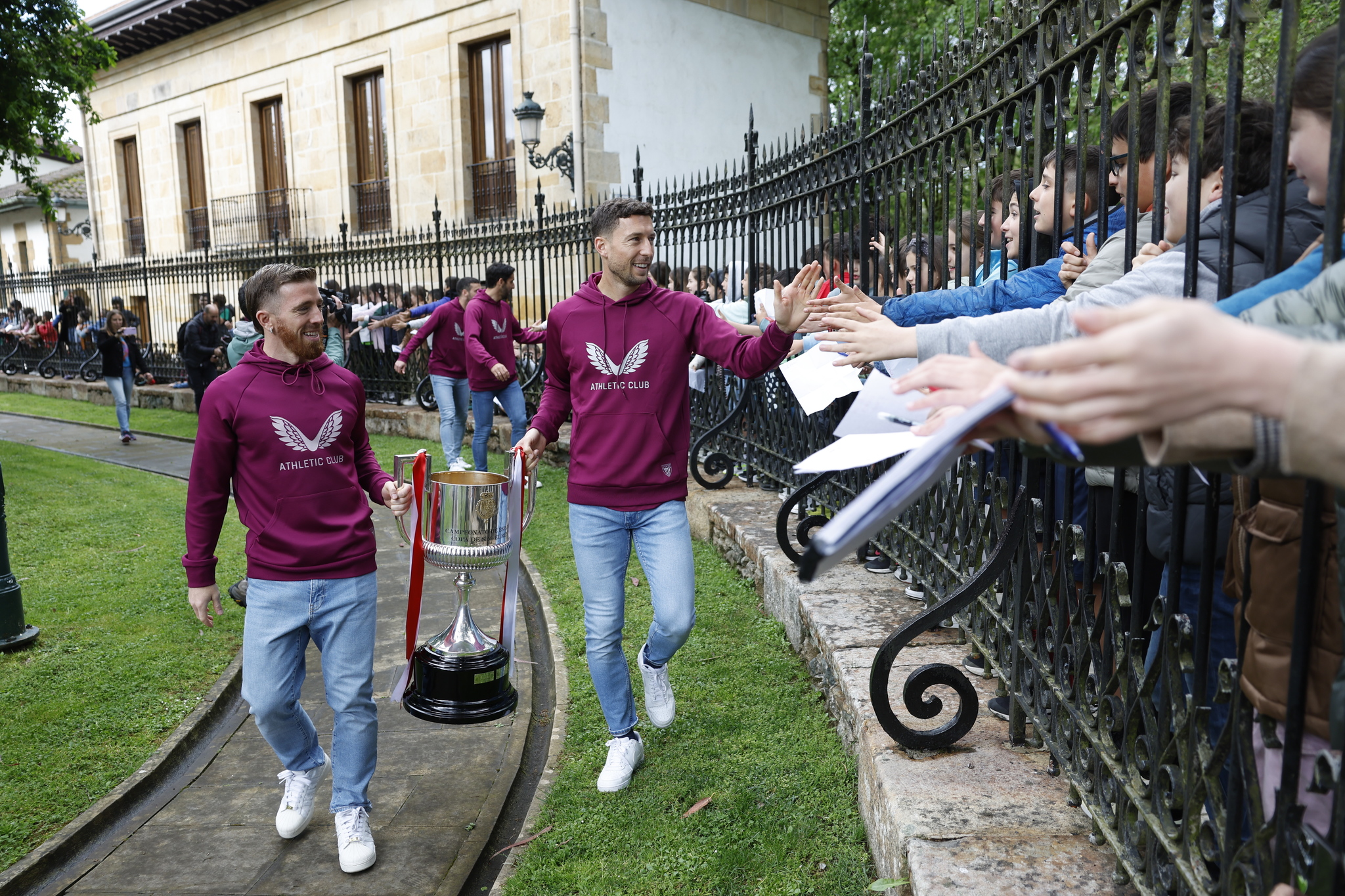 Muniain y De Marcos llevan la Copa en el primer recibimiento de la semana y saludan a escolares que esperan al otro lado de la valla de la Casa de Juntas de Gernika.