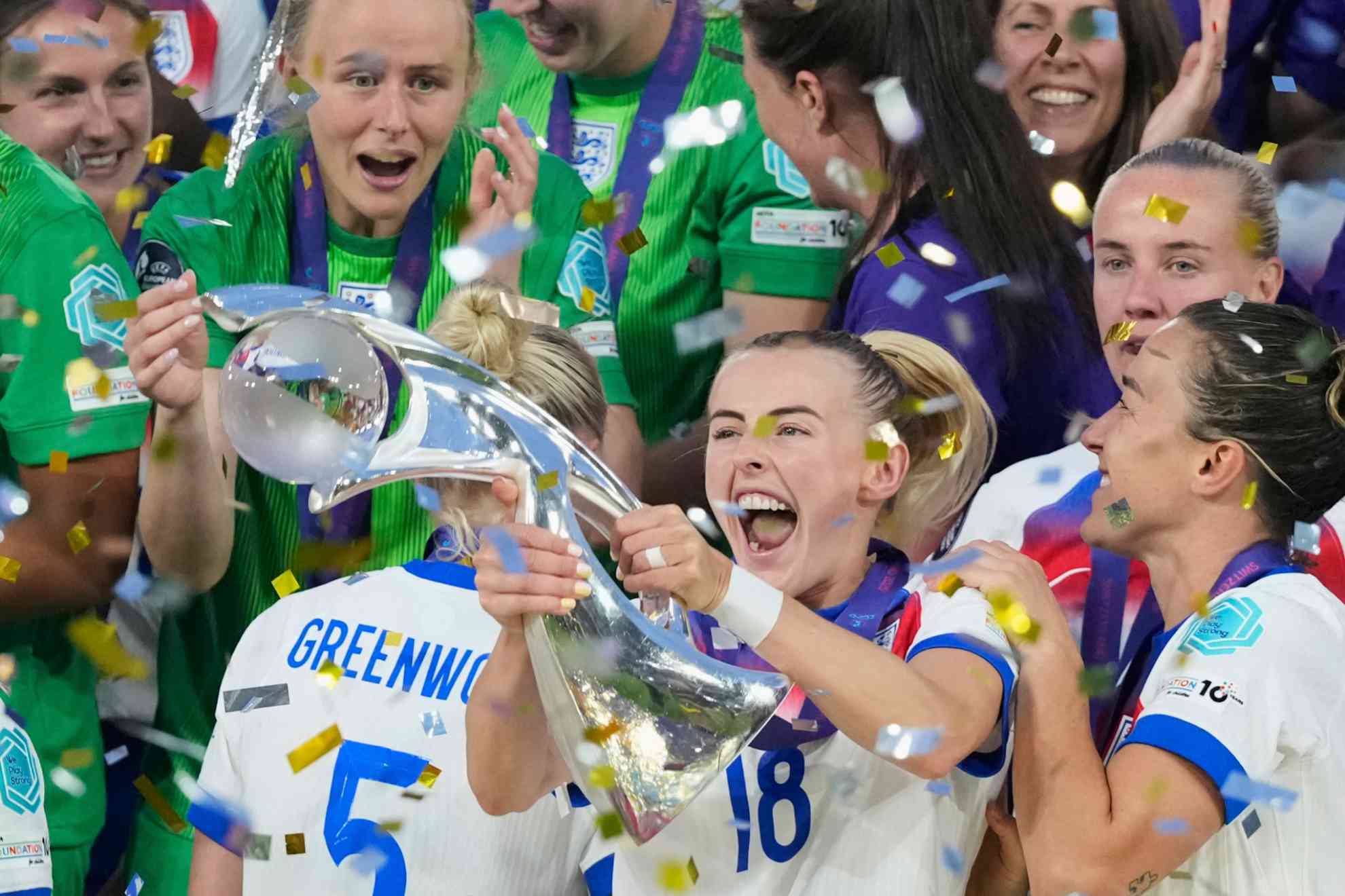 England's Chloe Kelly celebrates the trophy as left goalkeeper Hannah Hampton can be seen on the left after winning the final football match of the English and Spanish women's Euro 2025 at St. Jacob Park in Basel, Switzerland, on Sunday, July 27, 2025.