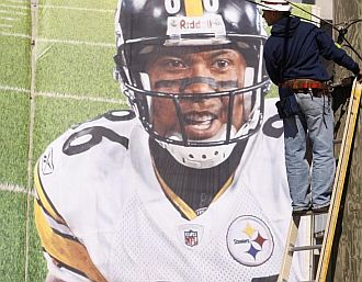 Un trabajador instala un cartel publicitario de los Pittsburgh Steelers en Tampa, Florida