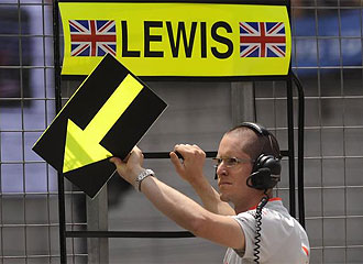 Un miembro de McLaren ensea un cartel a Hamilton