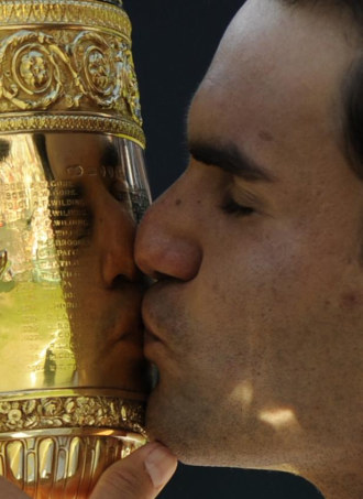 Roger Federer se mira en el trofeo de Wimbledon.