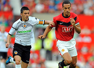 Rio Ferdinand lucha con Villa en un partido.