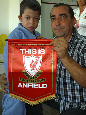 Un padre posa orgulloso junto a su hijo con el bandern del club ingls dedicado por Rafa Bentez