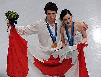 Tessa Virtue y Scott Moir posan con la bandera canadiense.