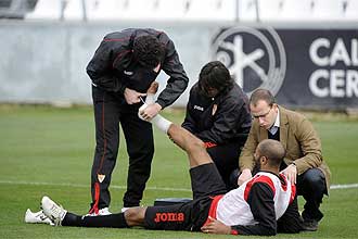 El Mdico del Sevilla atiende a Kanout tras lesionarse el tobillo en el entrenamiento de este jueves.