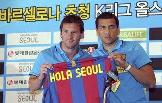 Alves y Messi sostienen una camiseta del Bara que saluda a la capital surcoreana