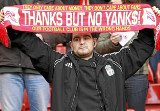 Un aficionado del Liverpool luce una bufanda en contra de propietarios norteamericanos.
