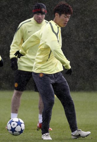 Ji-Sung Park realiza un pase ante la mirada de Rooney y bajo una ligera nevada en Manchester.