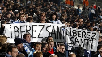 Familiares de Santos Mirasierra sostienen unas pancartas pidiendo su puesta en libertad durante un partido del Olympique.