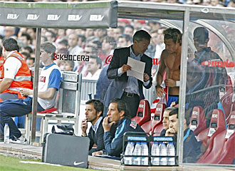 Fran Escribá, segundo entrenador del Atlético, da instrucciones a Diego Forlán mientras Quique Sánchez Flores observa el partido.