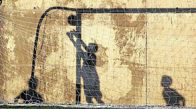 La sombra en el muro de los nios jugando y cmo el portero se estira para intentar llegar a detener el baln, durante una edicin del Torneo Alevn disputada en Brunete / RAFA CASAL