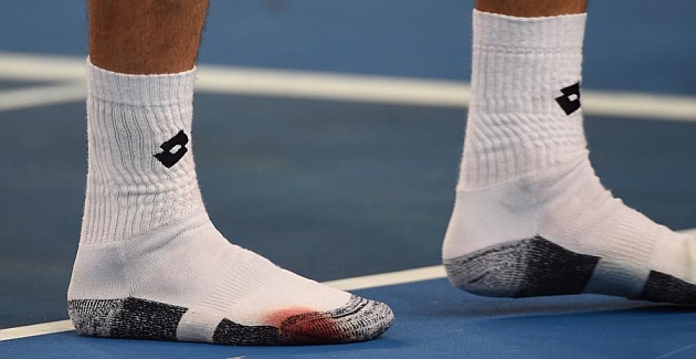 Ferrer muestra los calcetines sangrados tras su partido ante Simon en Australia / AFP