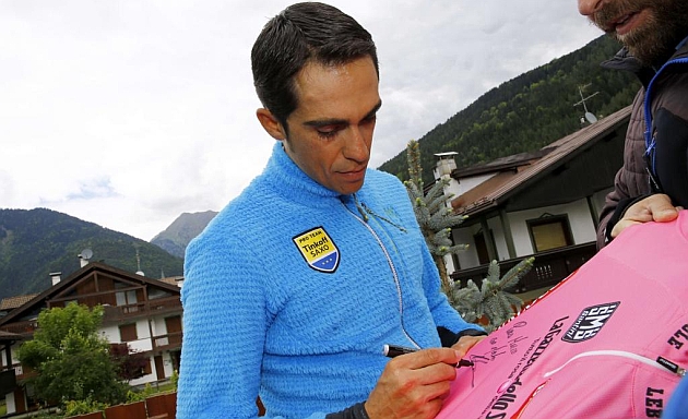Contador firma una maglia rosa en la puerta de su hotel. / Afp