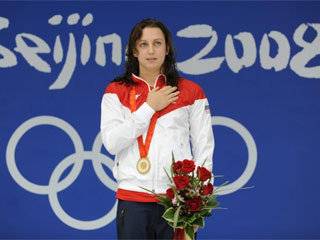 La nadadora estadounidense Rebecca Soni, escucha el himno tras lograr el oro en 200 metros braza (AFP)